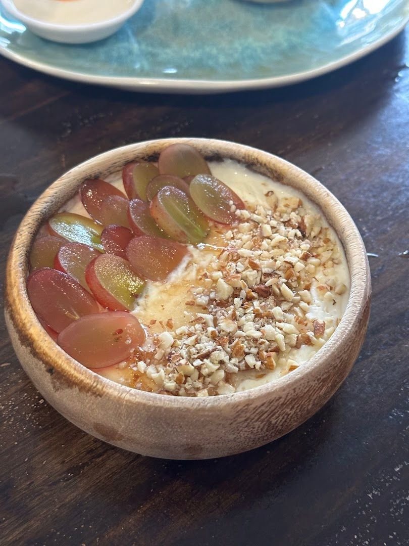 Yogurt bowl topped with fresh grapes and crushed nuts in a wooden bowl